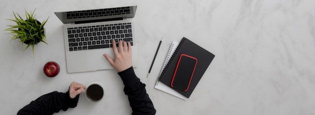 Vue de dessus d'une femme entrepreneur travaillant avec un ordinateur portable, un smartphone, des fournitures et une tasse de café