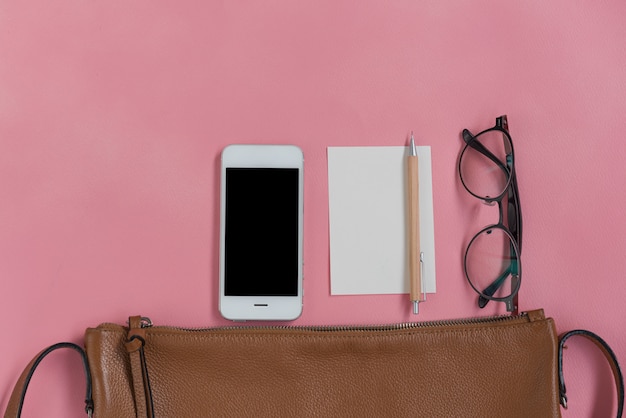 Vue de dessus de femme hipster travller des trucs avec téléphone, bloc-notes, lunettes et sac en cuir