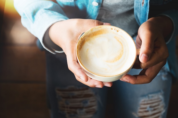 Photo vue de dessus de la femme en jeans tenir une tasse de café chaud