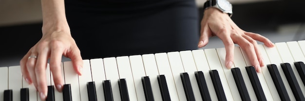 Vue de dessus d'une femme jouant sur un instrument de piano électrique touches différentes en noir et blanc