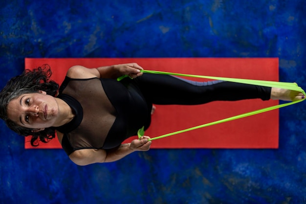 Vue de dessus d'une femme latino-américaine 38 faisant des exercices de tonification avec une bande de fitness élastique