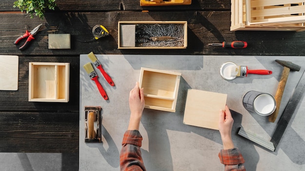 Une vue de dessus d'une femme méconnaissable fabriquant des boîtes en bois, une petite entreprise et un concept de bureau.