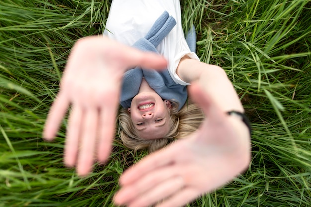 Vue de dessus d'une femme souriante posant dans l'herbe