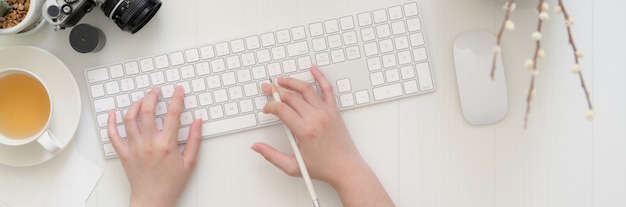 Vue de dessus d'une femme tapant sur le clavier de l'ordinateur sur la table de planche
