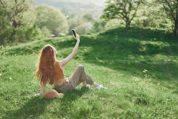 Vue de dessus d'une femme avec un téléphone à la main étudiante indépendante essayant de trouver une connexion internet dans la nature dans un parc d'été verdoyant