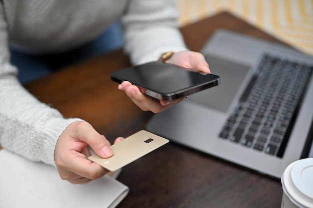 Vue de dessus Une femme tenant une carte de crédit et un smartphone au-dessus de son bureau