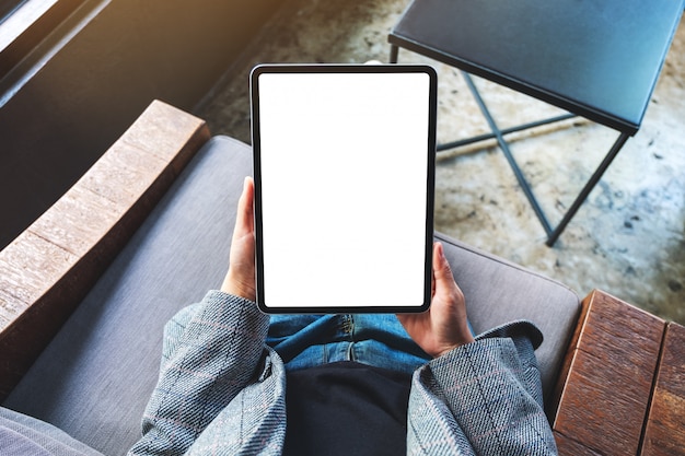 Vue de dessus d'une femme tenant un tablet pc noir avec écran de bureau blanc vierge