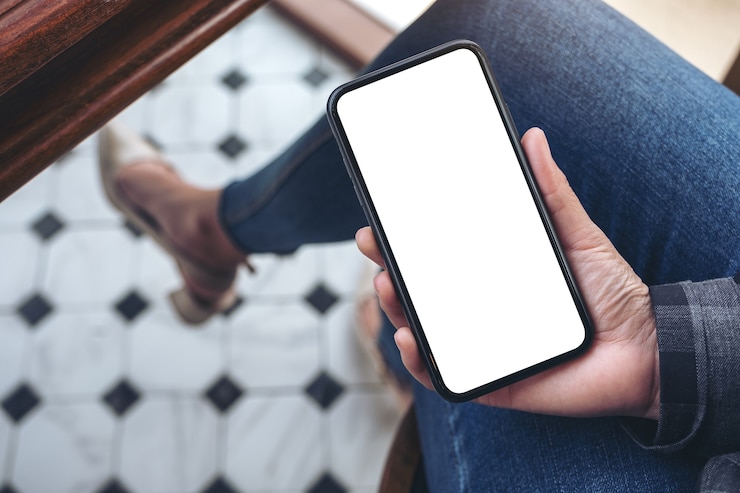 Photo vue de dessus femme tenant un téléphone intelligent noir avec écran de bureau blanc vierge alors qu'il était assis dans le café