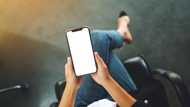 Vue de dessus d'une femme tenant un téléphone mobile noir avec écran de bureau blanc vierge