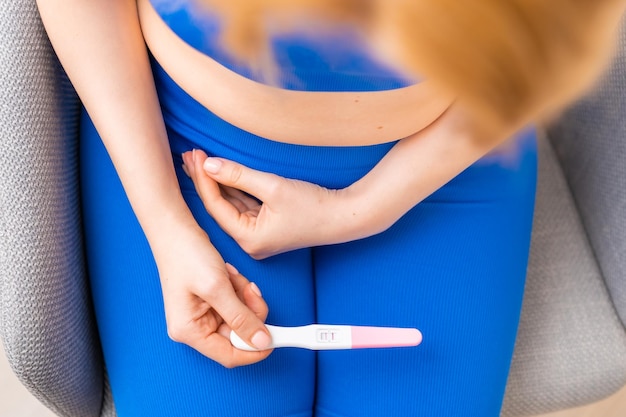 Vue de dessus sur la femme tenant un test de grossesse dans ses mains