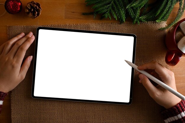 Vue de dessus Une femme utilisant une tablette numérique à son bureau avec une décoration de Noël