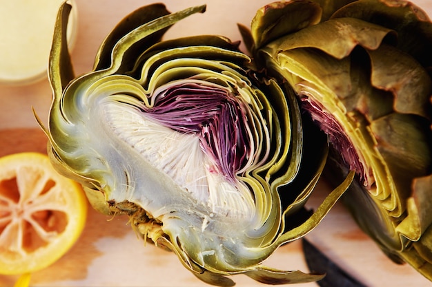 Vue de dessus fermer l&#39;artichaut demi-coupe avec la vinaigrette sur une planche à découper