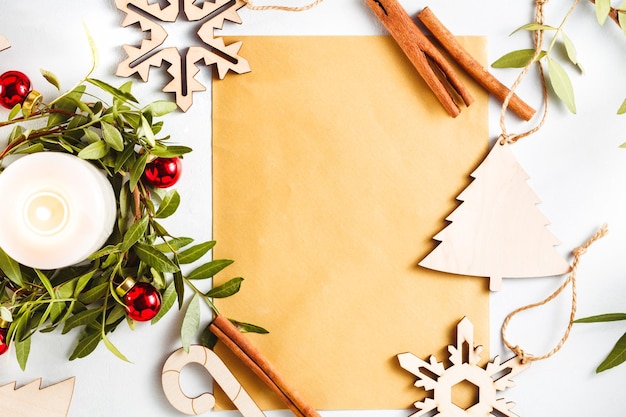 Vue de dessus sur une feuille dorée vide pour les salutations parmi les décorations de Noël sur fond blanc Maquette à plat