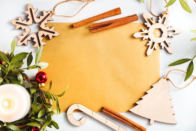Vue de dessus sur une feuille dorée vierge pour les salutations parmi les décorations de Noël sur fond blanc Maquette à plat