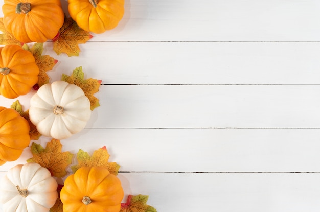 Photo vue de dessus des feuilles d'érable automne avec des citrouilles et des baies rouges sur un fond en bois blanc. concept de jour de thanksgiving.