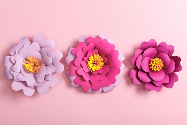 Vue de dessus des fleurs en papier colorées sur fond rose