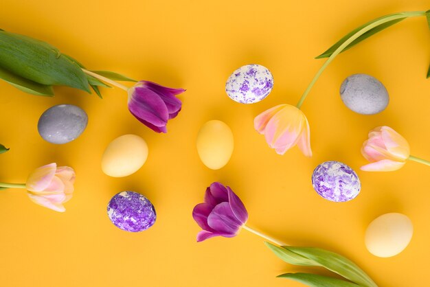 Vue de dessus fond jaune de Pâques avec des tulipes et des oeufs de Pâques