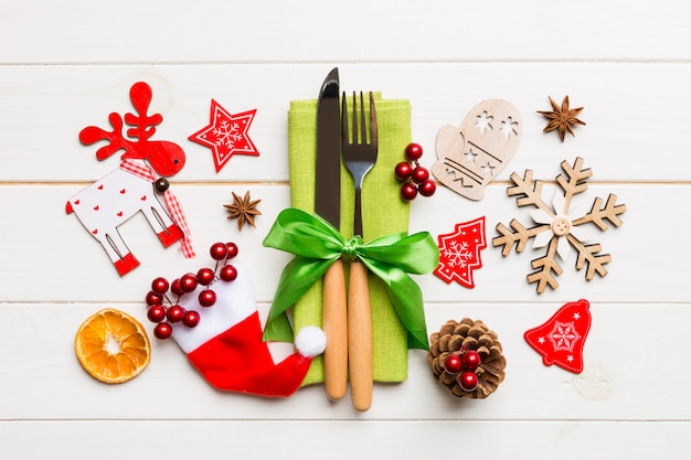 Vue de dessus de fourchette et couteau sur la serviette en bois, différentes décorations de Noël et jouets, concept de dîner de nouvel an