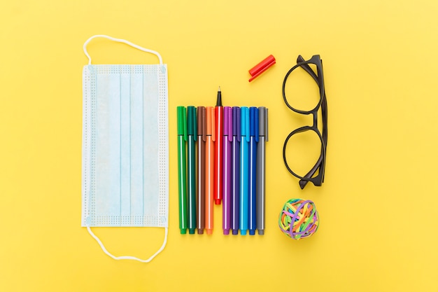 Photo vue de dessus des fournitures scolaires avec masque et lunettes