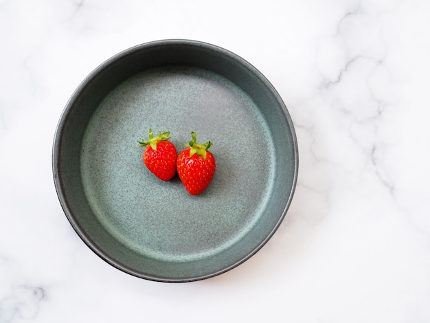 Vue de dessus de la fraise rouge dans la plaque verte isolée sur le mur de la table en marbre.