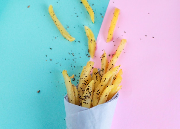 Vue de dessus des frites isolées avec saupoudrage d'algues sur fond bleu et rose