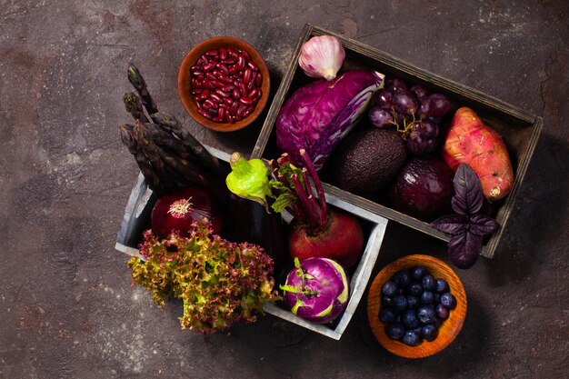 Vue de dessus des fruits et légumes sains dans des bols et des boîtes en bois sur fond gris