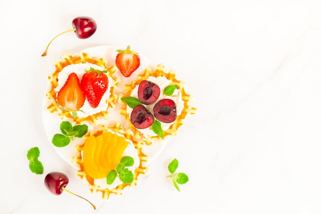 Vue de dessus des gaufres belges traditionnelles avec du fromage à pâte molle, des fruits et des baies