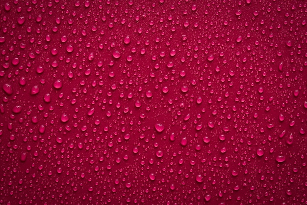 Vue de dessus. Gouttes d'eau sur une surface rouge foncé. Macro photo, goutte, base en plastique d'ombre.