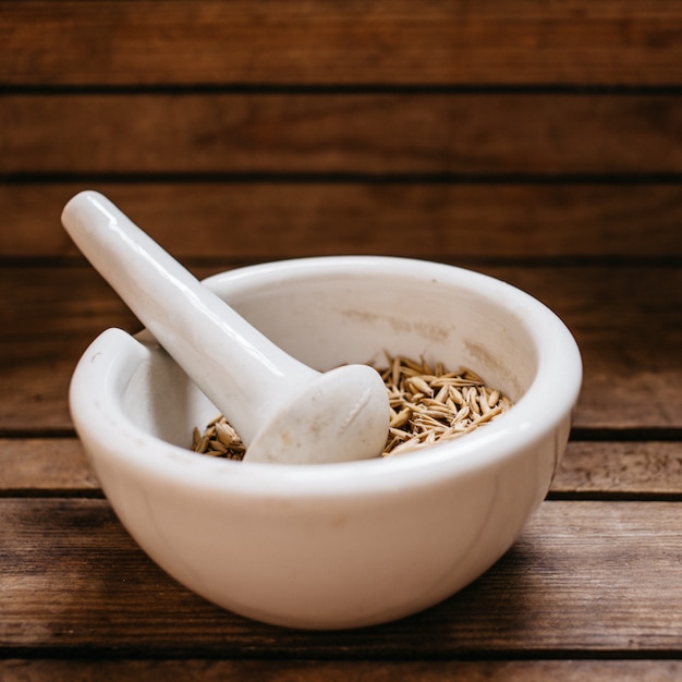 Vue de dessus des grains d&#39;avoine dans le bol de mortier en porcelaine sur la vieille table en bois