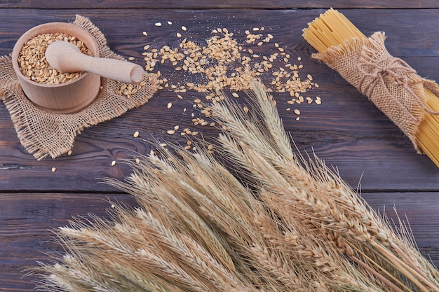 Vue de dessus des grains de blé avec broyeur à mortier et spaghettis sur bois foncé