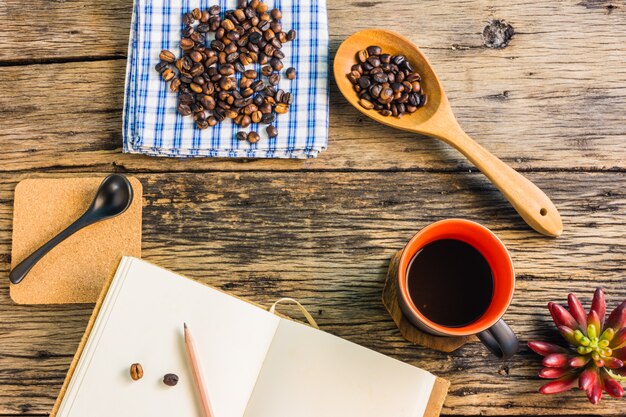 Vue de dessus, grains de café torréfiés, café et notes sur la table en bois.