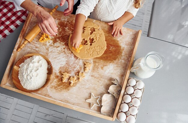 Vue de dessus d'une grand-mère aînée qui, avec sa petite-fille, prépare des bonbons pour Noël dans la cuisine