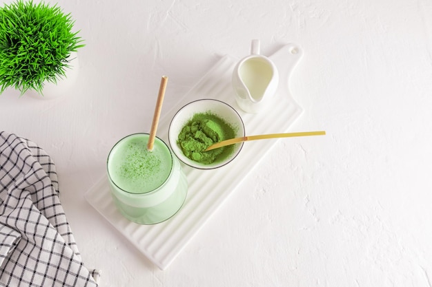 Vue de dessus d'un grand verre de thé vert matcha et de lait fouetté sur une planche en céramique blanche un bol de poudre de thé vert boisson saine Detox