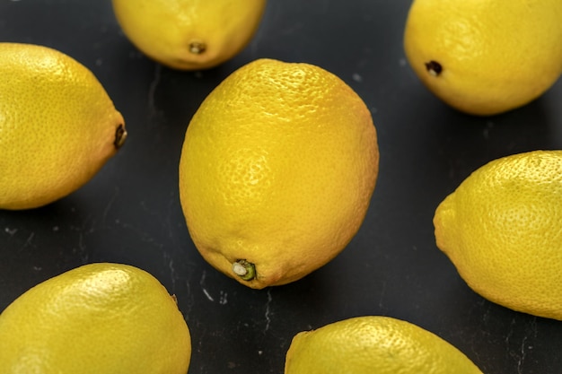 Vue de dessus, gros plan de citrons sur planche de marbre noir.