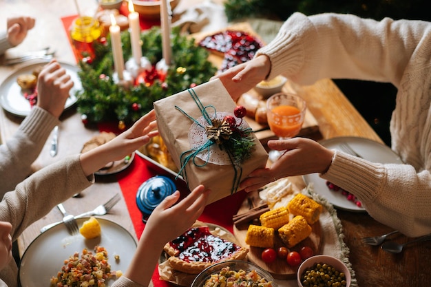 Vue de dessus en gros plan d'un parent aimant méconnaissable donnant une boîte de fête avec un cadeau de Noël à heureux