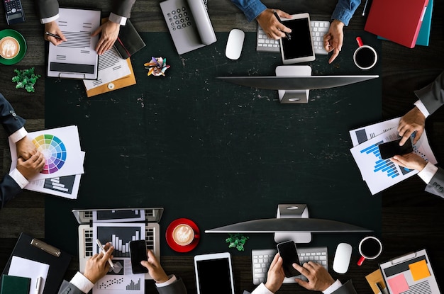 Vue de dessus d'un groupe d'affaires de personnes multiethniques occupées rencontrant d'autres personnes dans un bureau moderne avec un ordinateur portable, un smartphone, une tablette, un café et un document sur tablexA