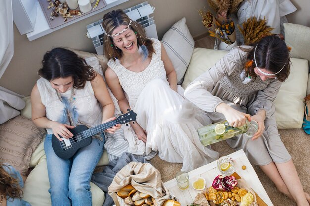 Vue de dessus groupe de femmes hippie passer du temps ensemble à la fête des poules manger chant chant souriant