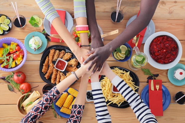 Photo vue de dessus d'un groupe de personnes en train de dîner ensemble assis à une table en bois nourriture sur la table les gens mangent de la restauration rapide