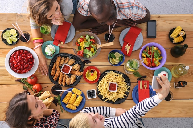 Photo vue de dessus d'un groupe de personnes en train de dîner ensemble assis à une table en bois nourriture sur la table les gens mangent de la restauration rapide