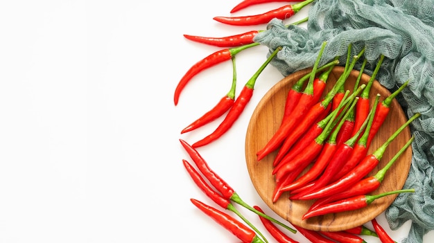 vue de dessus ou groupe plat de piment rouge dans une plaque de bois sur fond blanc.