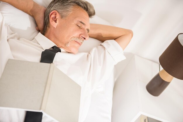 Vue de dessus de l'homme d'affaires dort en costume avec un ordinateur portable sur le lit dans la chambre d'hôtel