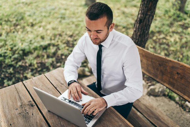 Vue de dessus d'un homme d'affaires intelligent portant une chemise blanche en tapant sur son ordinateur faisant un rapport de son entreprise