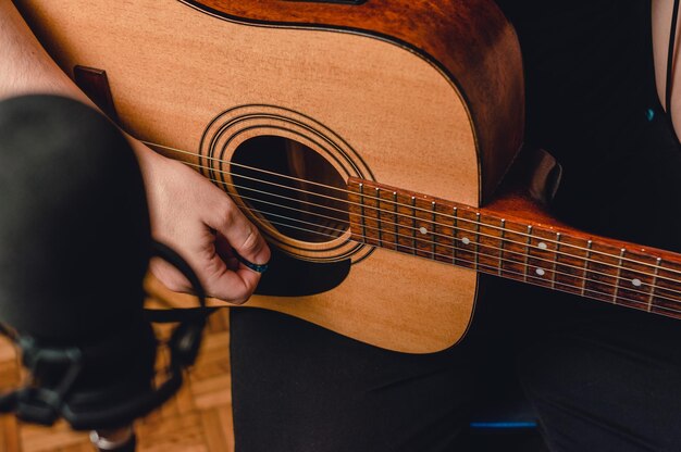 Vue de dessus homme enregistrant de la musique avec une guitare acoustique et un microphone flou au premier plan