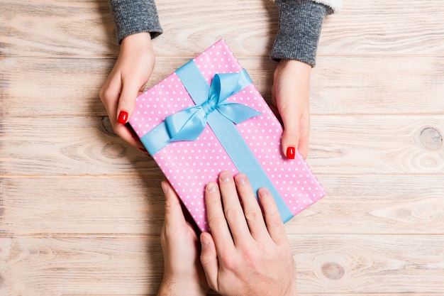 Vue de dessus un homme et une femme se félicitant mutuellement avec un cadeau en bois. Surprise pour des vacances. Fermer