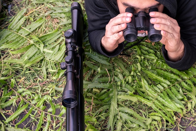 Vue de dessus homme avec jumelles et fusil sur sol en herbe