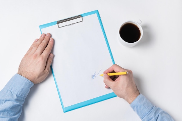 Vue de dessus de l'homme mains papiers et tasse de café L'homme signe le motif de toile de fond de l'espace de copie papier