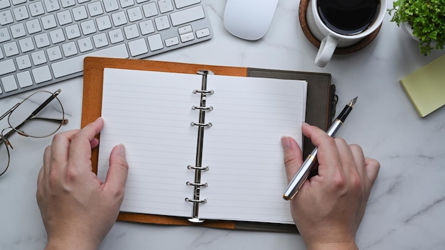 Vue de dessus homme tenant un stylo et un cahier vide