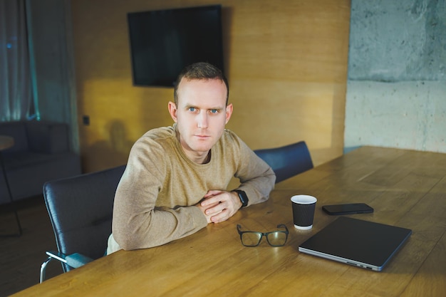 Vue de dessus d'un homme en vêtements décontractés avec un café assis sur le lieu de travail à l'aide d'un netbook tout en travaillant pendant la journée de travail Un homme d'affaires prospère travaille sur un ordinateur portable