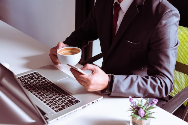 Vue de dessus des hommes d&#39;affaires se détendre avec du café tout en utilisant un téléphone intelligent dans le lieu de travail