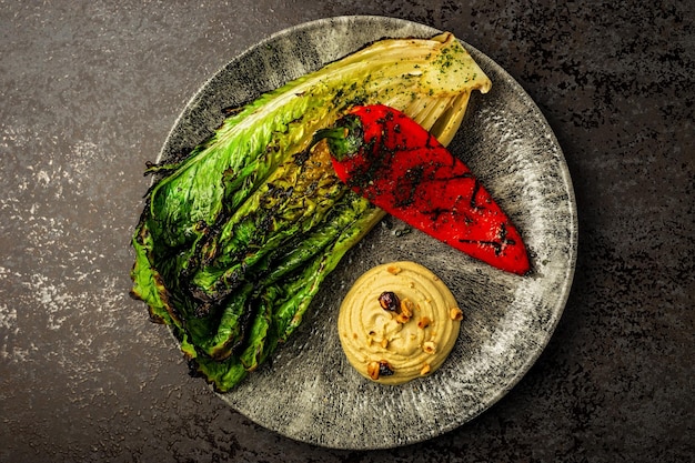 Vue de dessus de l'houmous aux noix de légumes grillés chou frisé et poivron rouge servi sur une assiette dans un restaurant